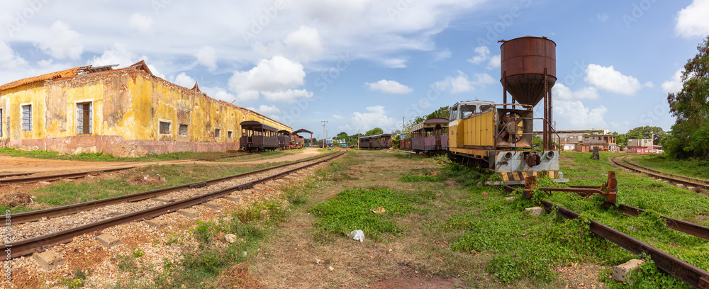 View of an Abandonned rail road station with an old train during a sunny and cloudy day. Taken in Trinidad, Cuba.