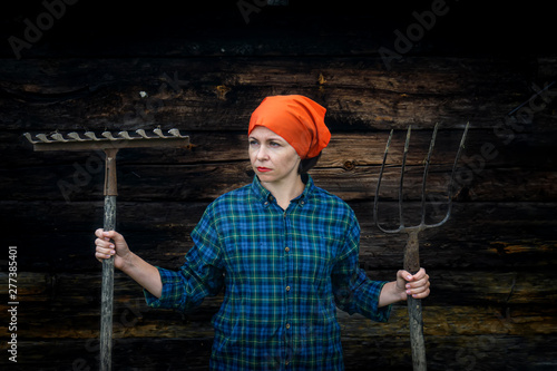 Young woman stands with a pitchfork near a stable on a ranch. photo