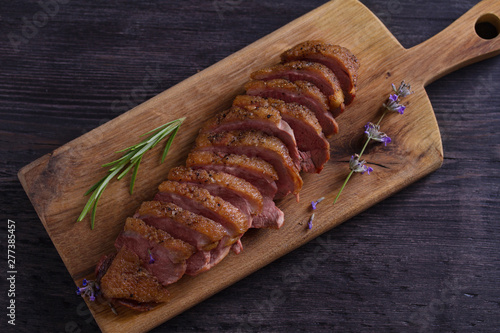Sliced duck breast, lavender honey and rosemary on serving board