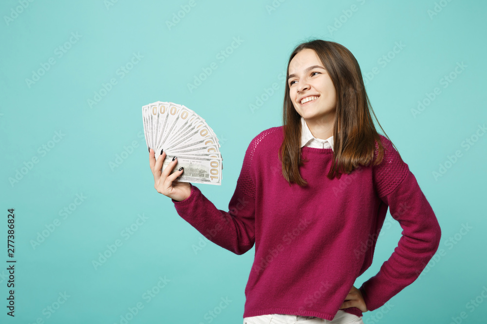 Young brunette woman girl in casual clothes posing isolated on blue background studio portrait. People emotions lifestyle concept. Mock up copy space Hold in hand fan of cash money in dollar banknotes Young brunette woman girl in casual clothes posing isolated on blue background studio portrait. People emotions lifestyle concept. Mock up copy space Hold in hand fan of cash money in dollar banknotes