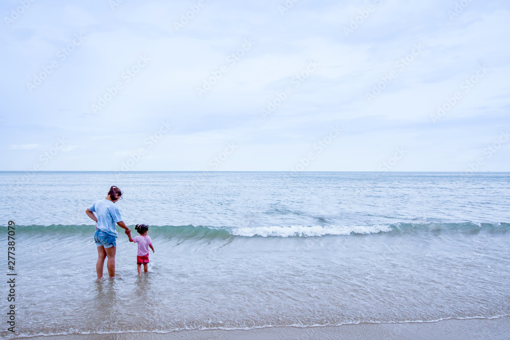 Asian daughter holding her mother’s hand on the beach. Asian daughter holding her mother’s hand on the beach.