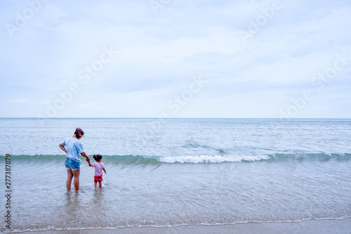 Asian daughter holding her mother’s hand on the beach.