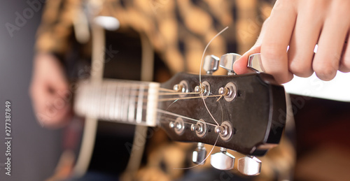 The young man tuning the electric guitar.