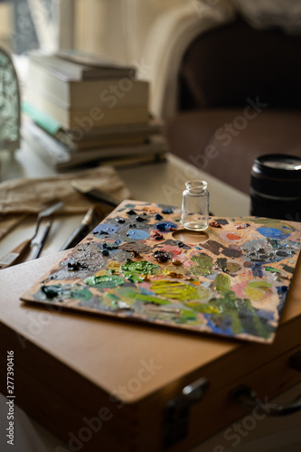 Art studio with a palette full of different colors of oil paint in a table