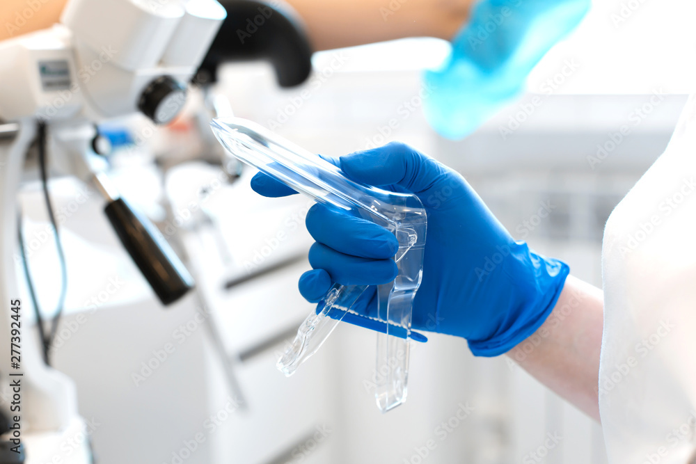 the gynecologist holds in his hand a mirror for vaginal examination of the patient the gynecologist holds in his hand a mirror for vaginal examination of the patient