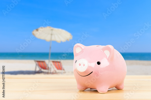 Piggy bank on wooden desk, on beach sea background, saving for vacation concept © wirojsid