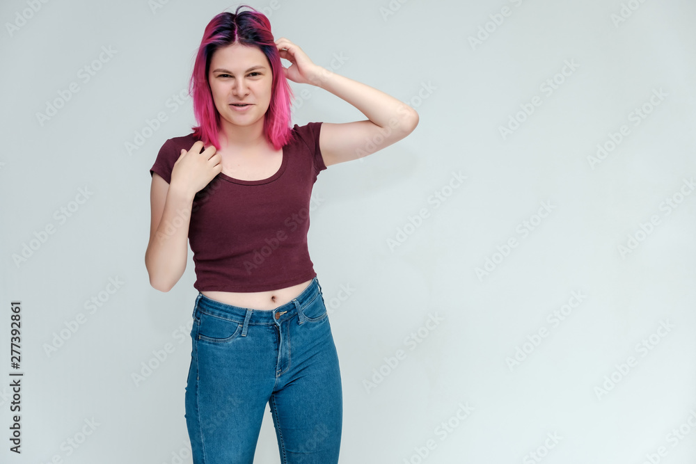 Full-length portrait of a young pretty teenager girl in jeans and a vest with beautiful purple hair on a white background in the studio. Talking, smiling, showing hands with emotions. Full-length portrait of a young pretty teenager girl in jeans and a vest with beautiful purple hair on a white background in the studio. Talking, smiling, showing hands with emotions.