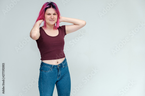 Full-length portrait of a young pretty teenager girl in jeans and a vest with beautiful purple hair on a white background in the studio. Talking, smiling, showing hands with emotions.