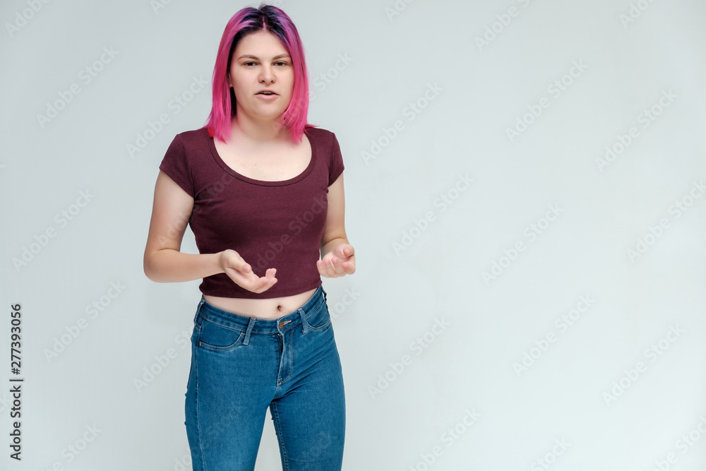 Full-length portrait of a young pretty teenager girl in jeans and a vest with beautiful purple hair on a white background in the studio. Talking, smiling, showing hands with emotions. Full-length portrait of a young pretty teenager girl in jeans and a vest with beautiful purple hair on a white background in the studio. Talking, smiling, showing hands with emotions.