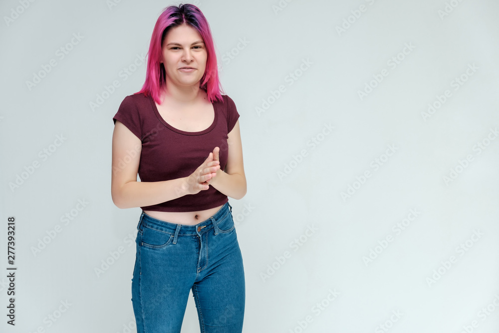 Full-length portrait of a young pretty teenager girl in jeans and a vest with beautiful purple hair on a white background in the studio. Talking, smiling, showing hands with emotions. Full-length portrait of a young pretty teenager girl in jeans and a vest with beautiful purple hair on a white background in the studio. Talking, smiling, showing hands with emotions.