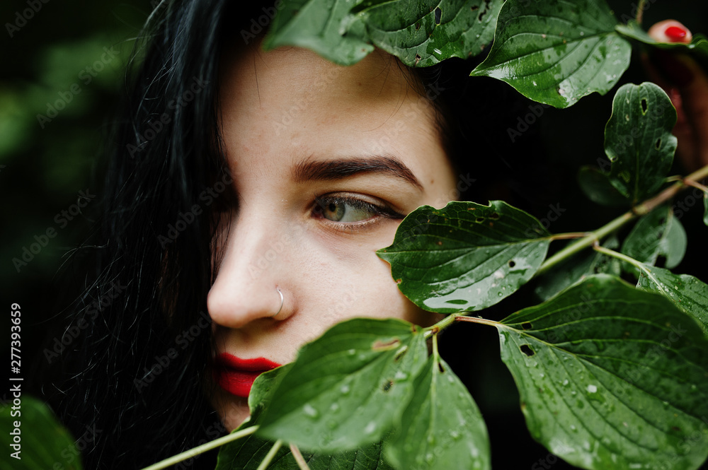 Close up portrait of sensual brunette girl with red lips. Goth dramatic woman at tree branch. Close up portrait of sensual brunette girl with red lips. Goth dramatic woman at tree branch.