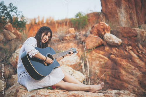 Fototapeta Naklejka Na Ścianę i Meble -  Portrait of bohemian woman play guitar on sunset,Lifestyle of modern thailand girl,Happy woman concept,Thailand people