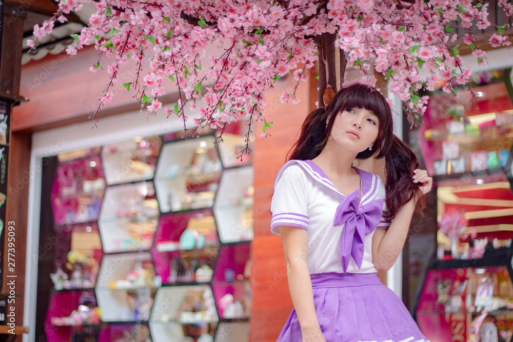 Beautiful Asian model in Japanese student uniform with cherry blossom flower background