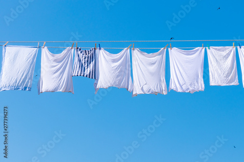 close up of white shirts hanging for dry with the sun background with blue clear sky in summer season.