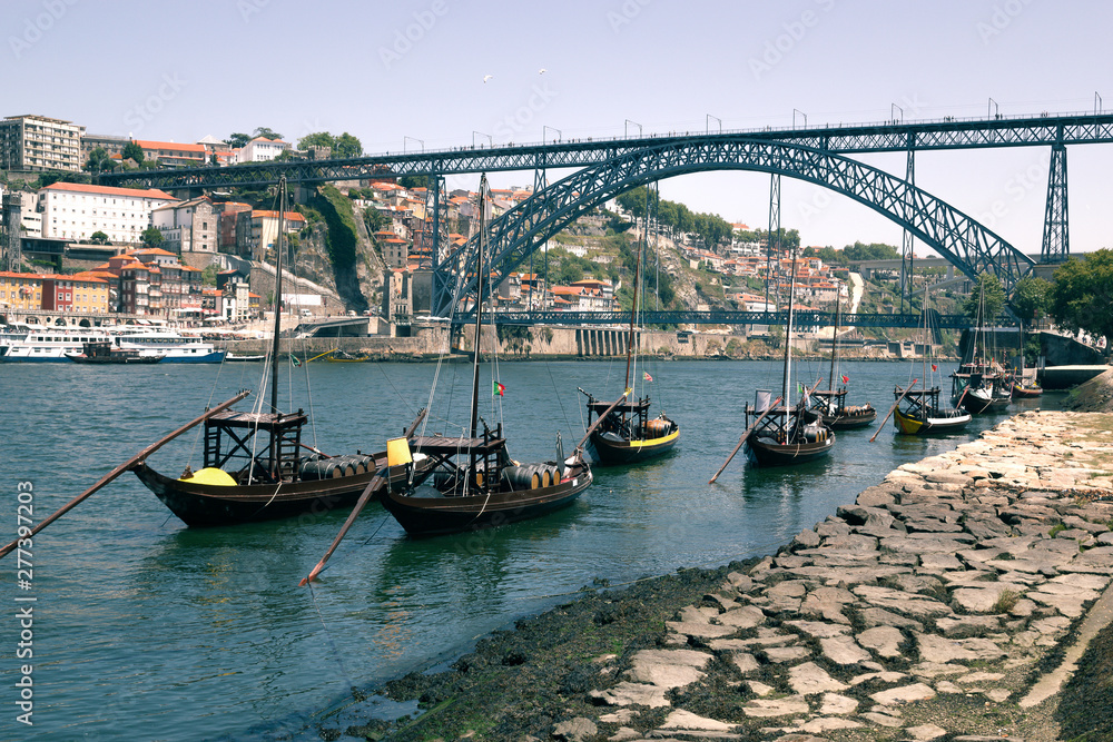 Landscape view of typical boats and Luis I Bridge in Porto, Portugal. Landscape view of Luis I bridge in Porto, Portugal. In the river sail the typical Portuguese boats with barrels of wine. Travel.