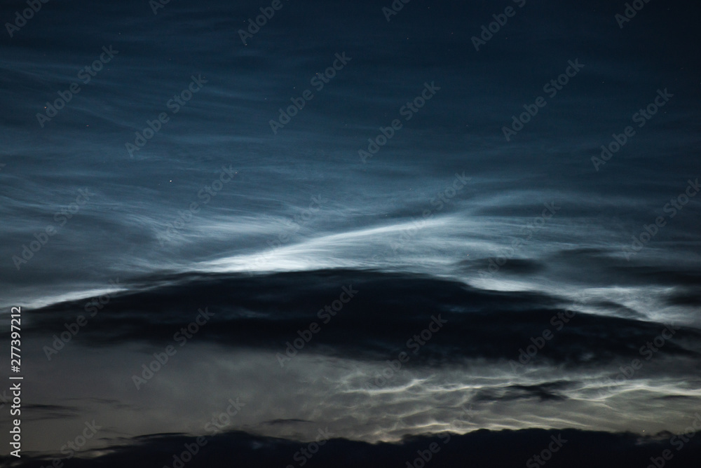 Noctilucent clouds close up on a summer night. Glowing clouds in the night sky.