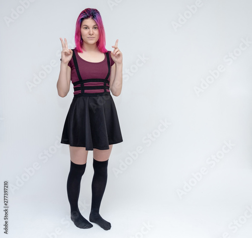 Wallpaper Mural Full-length portrait of young pretty teenager girl in burgundy T-shirt and black dress with beautiful purple hair on a white background in the studio. Talking, smiling, showing hands with emotions. Torontodigital.ca
