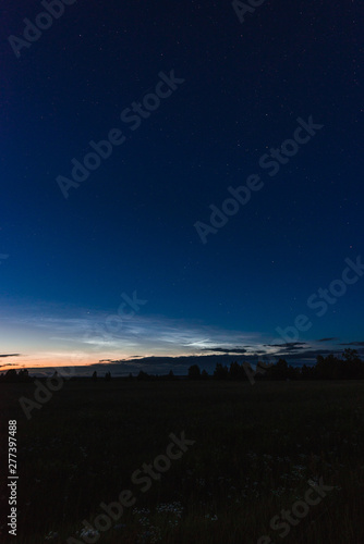 Noctilucent clouds on a summer night above p. Glowing clouds in the night sky.