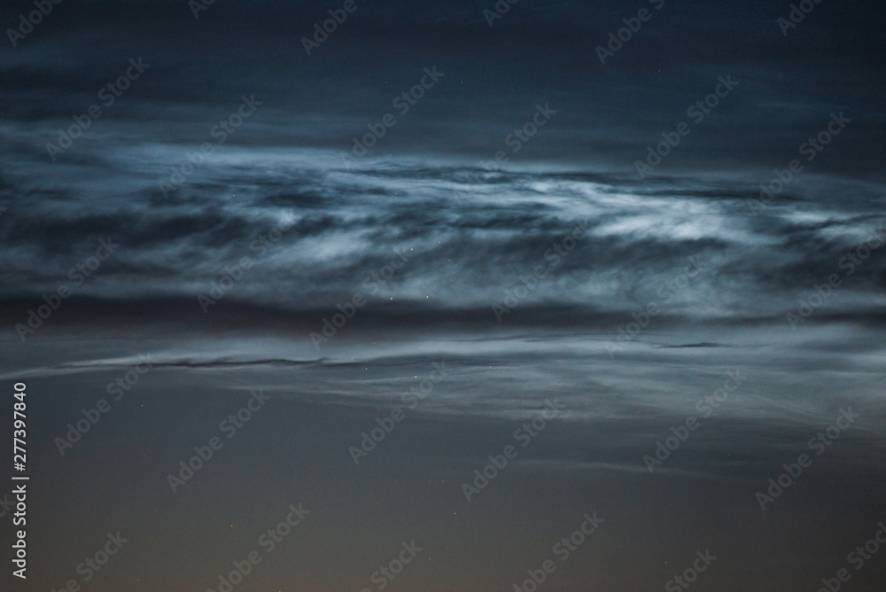 Noctilucent clouds close up on a summer night. Glowing clouds in the night sky. Noctilucent clouds close up on a summer night. Glowing clouds in the night sky.