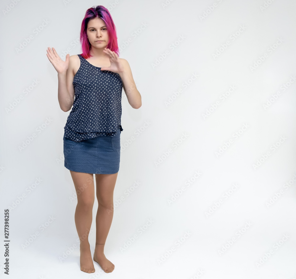 Full-length portrait of a young pretty girl teenager in a T-shirt and skirt with beautiful purple hair on a white background in the studio. Talking, smiling, showing hands with emotions. Full-length portrait of a young pretty girl teenager in a T-shirt and skirt with beautiful purple hair on a white background in the studio. Talking, smiling, showing hands with emotions.
