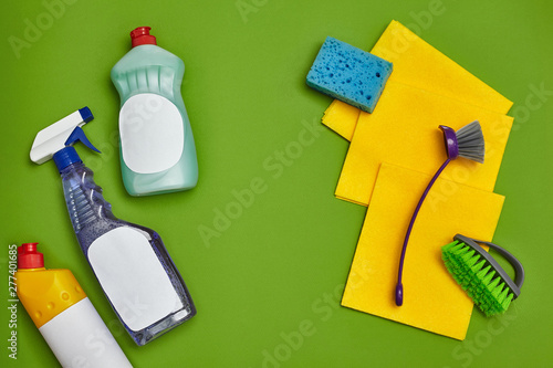 Detergents and cleaning accessories on a green background. Housekeeping concept.