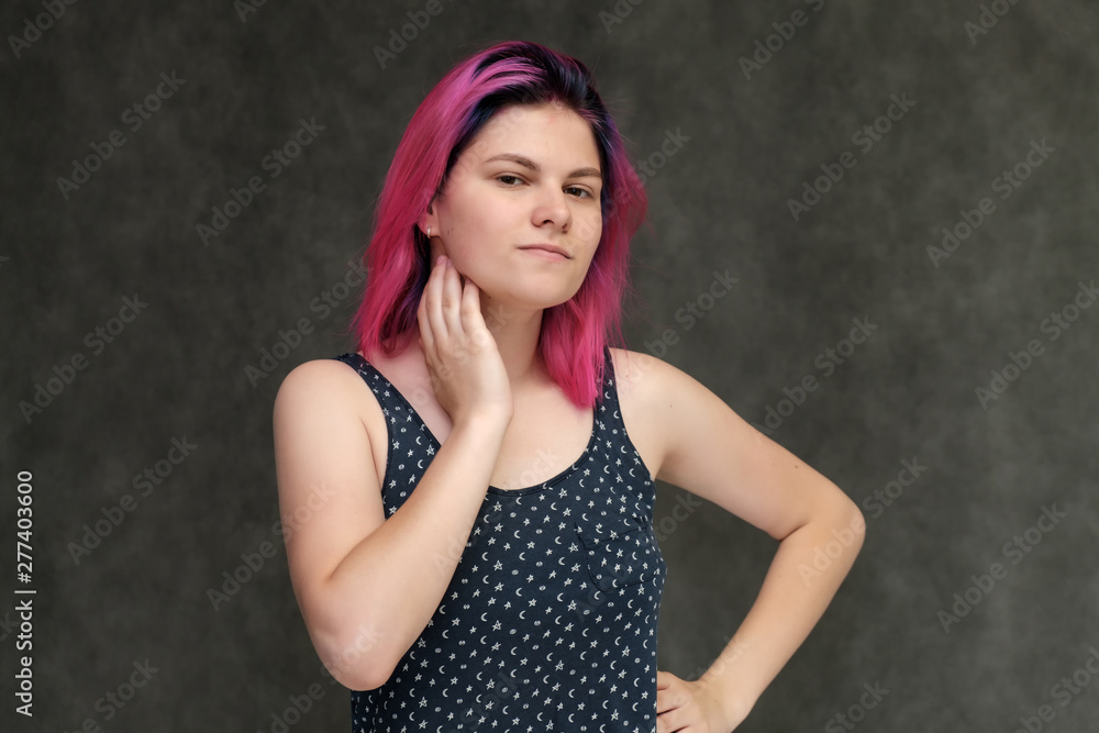 Portrait to the waist of a young pretty girl teenager in a T-shirt with beautiful purple hair on a gray background in the studio. Talking, smiling, showing hands with emotions. Portrait to the waist of a young pretty girl teenager in a T-shirt with beautiful purple hair on a gray background in the studio. Talking, smiling, showing hands with emotions.