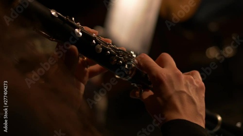Handheld close-up of a clarinet being played by a woman during a concert.