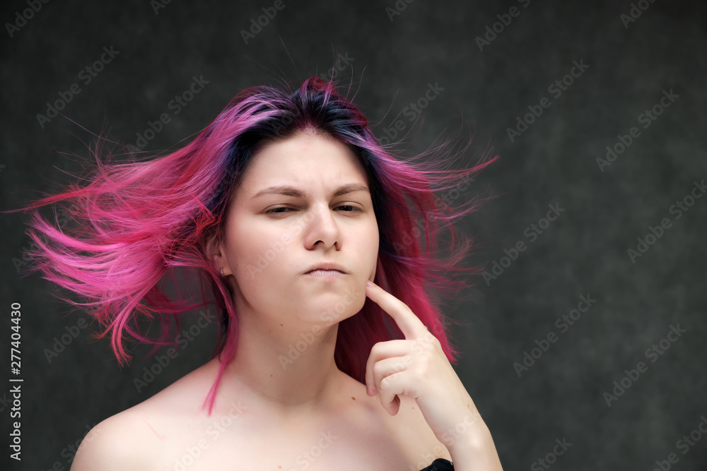 Obraz premium Close-up portrait of a young pretty teen girl with beautiful purple hair on a gray background in the studio. Smiles with emotions