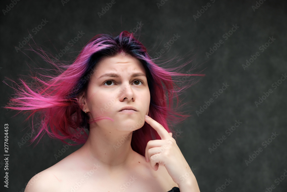 Fototapeta premium Close-up portrait of a young pretty teen girl with beautiful purple hair on a gray background in the studio. Smiles with emotions