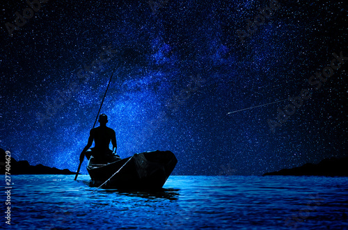 African boatman with his canoe in front of the stars photo
