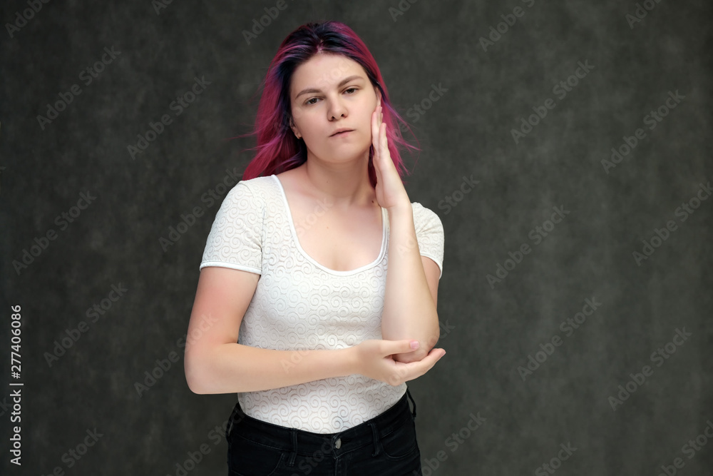 Portrait to waist of a young beautiful girl teenager in a white T-shirt with beautiful purple hair on a gray background in the studio. They say, they smile, they show hands with emotions. Portrait to waist of a young beautiful girl teenager in a white T-shirt with beautiful purple hair on a gray background in the studio. They say, they smile, they show hands with emotions.