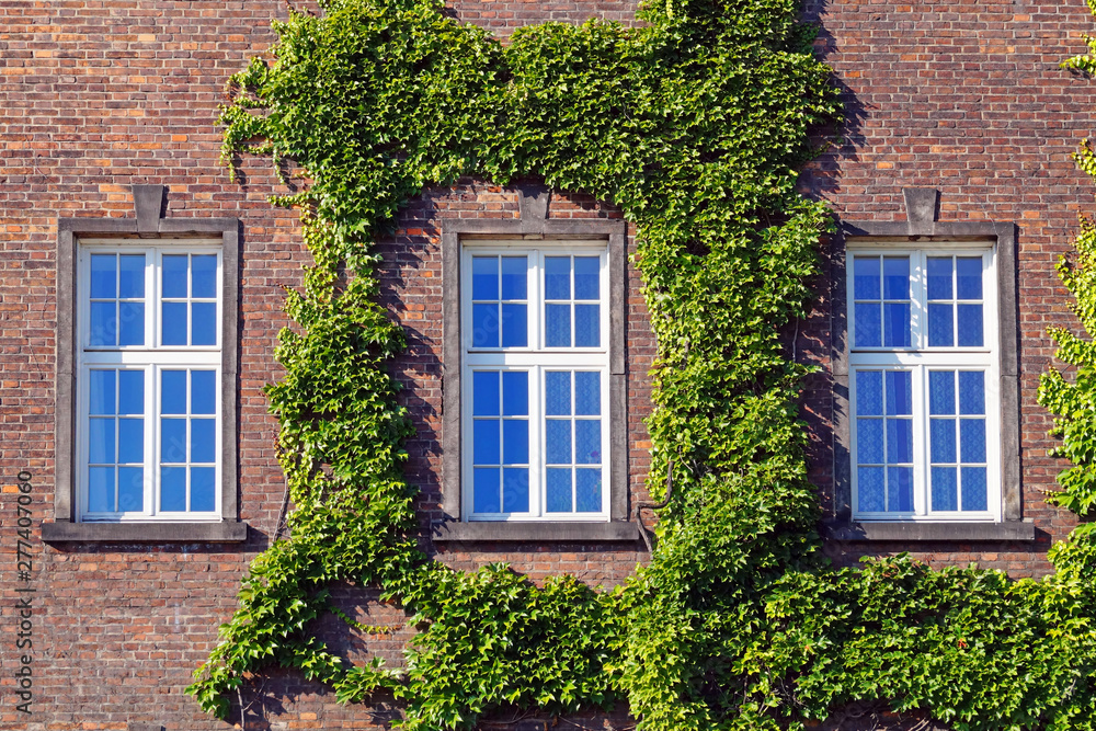 Three window on a red brick wall.