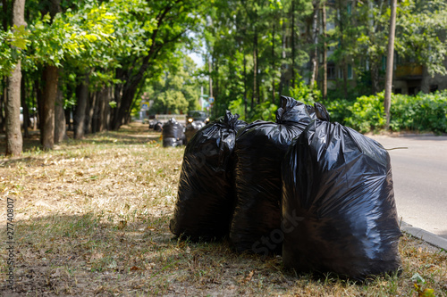 black bags of garbage are under the trees. Garden cleaning concept