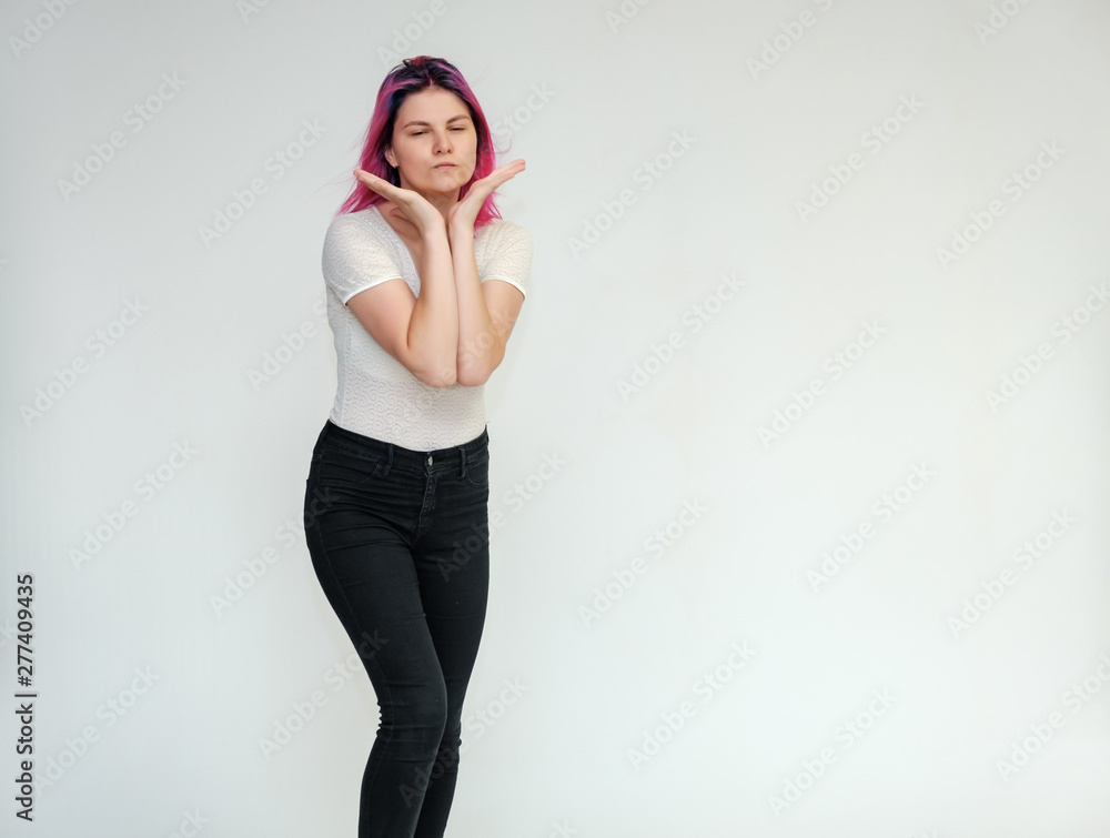 Portrait below the knee of a young beautiful girl teenager in a white T-shirt and black jeans with beautiful purple hair on a white background in the studio. They say, they smile, they show hands Portrait below the knee of a young beautiful girl teenager in a white T-shirt and black jeans with beautiful purple hair on a white background in the studio. They say, they smile, they show hands
