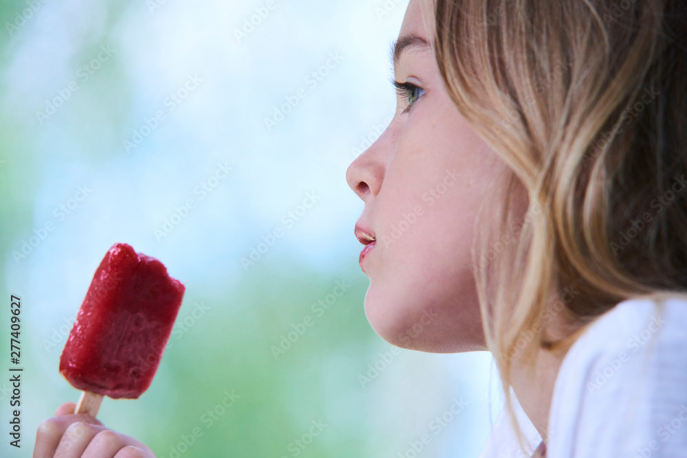Beautiful little girl eats strawberry ice-cream in the summer. Selective focus Beautiful little girl eats strawberry ice-cream in the summer. Selective focus