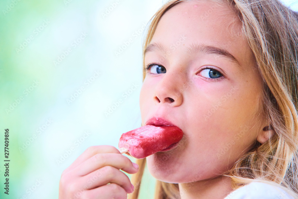 Beautiful little girl eats strawberry ice-cream in the summer. Selective focus Beautiful little girl eats strawberry ice-cream in the summer. Selective focus