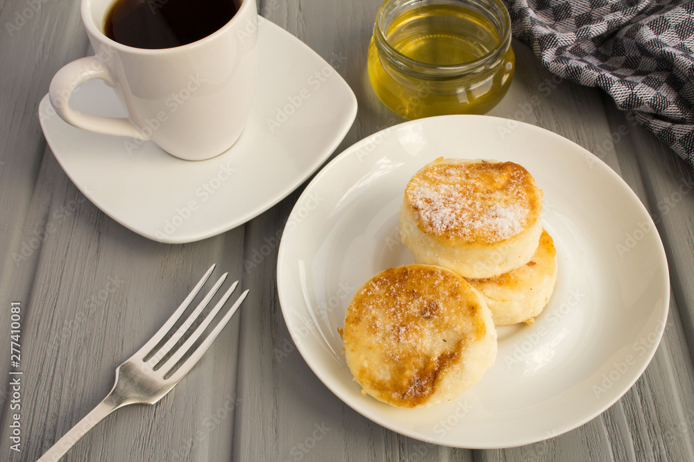 Breakfast: cheese pancakes, coffee and honey on the grey wooden background Breakfast: cheese pancakes, coffee and honey on the grey wooden background