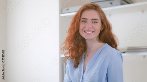 Portrait redhead young woman wearing in casual blue shirt posing looking at he camera smiling.