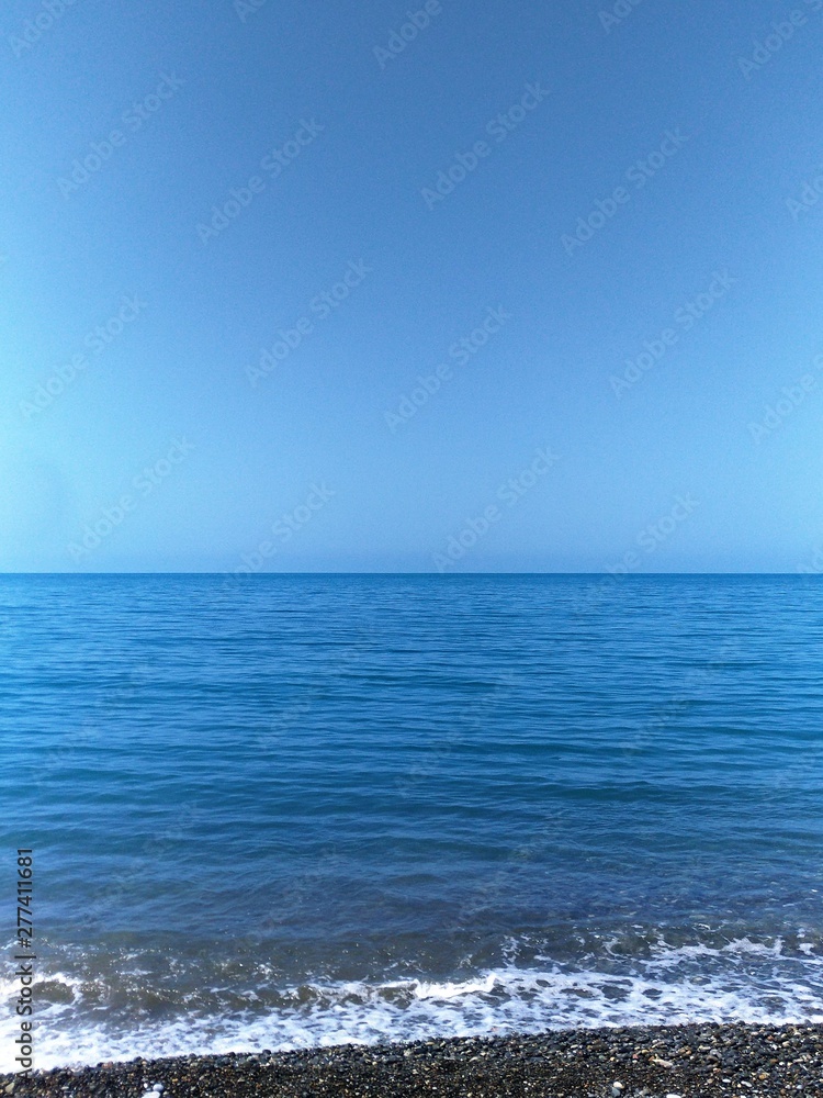 Fototapeta premium seascape in blue tones, the horizon line is located in the center of the image, there is free space for text, copy space, vertical