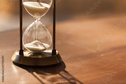 Sand running through the bulbs of an hourglass measuring the passing time in a countdown to a deadline with copy space.