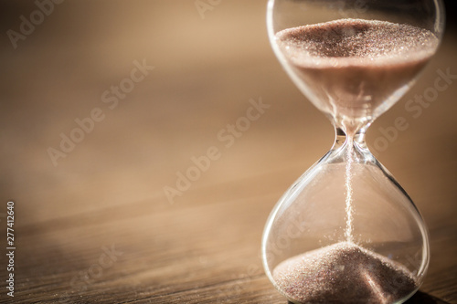 Sand running through the bulbs of an hourglass measuring the passing time in a countdown to a deadline with copy space. photo