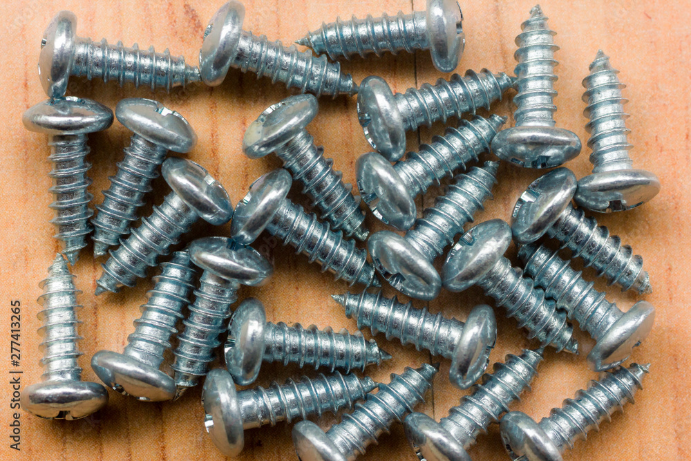 Metal screws on wooden background