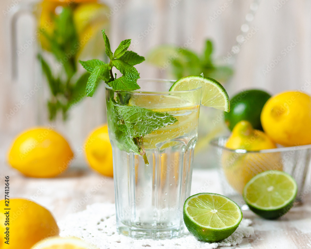 Summer composition with refreshing healthy alcohol free home made lemonade with pepper mint, limes and lemons. White lace napkin as decor, wooden background. Vacation mood, enjoying summertime Summer composition with refreshing healthy alcohol free home made lemonade with pepper mint, limes and lemons. White lace napkin as decor, wooden background. Vacation mood, enjoying summertime