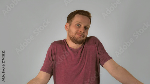 caucasian guy with red hair showing emotion surprise and misunderstanding. handsome redheaded men wearing in casual t-shirt. Portrait ginger young caucasian man on grey background