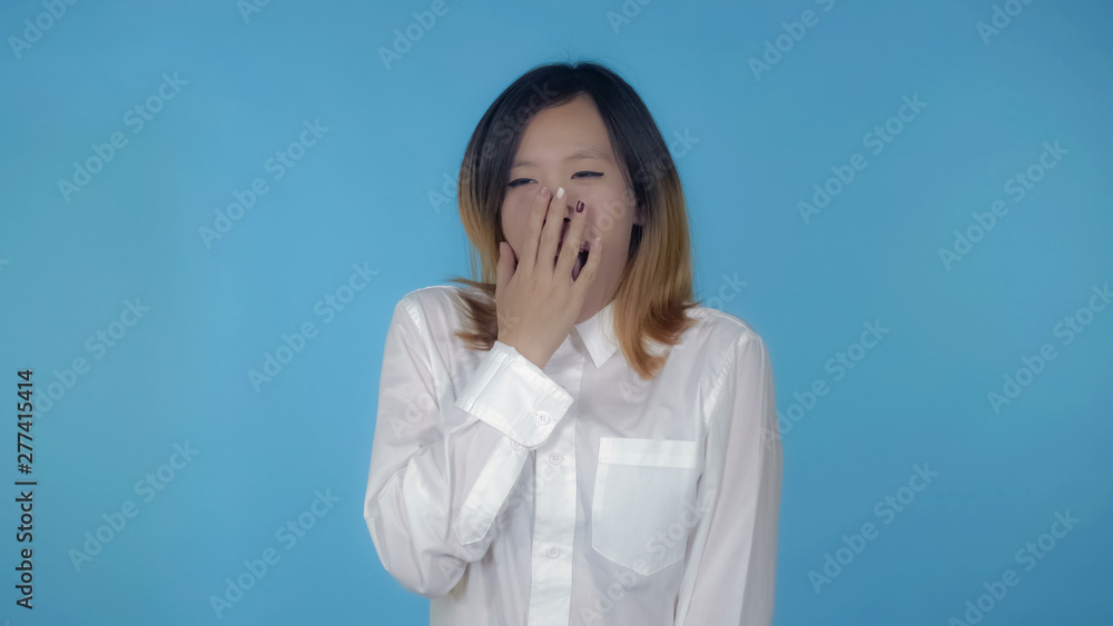 young asian woman tired and overworked on blue background in studio. attractive millennial girl wearing white casual shirt looking at the camera young asian woman tired and overworked on blue background in studio. attractive millennial girl wearing white casual shirt looking at the camera