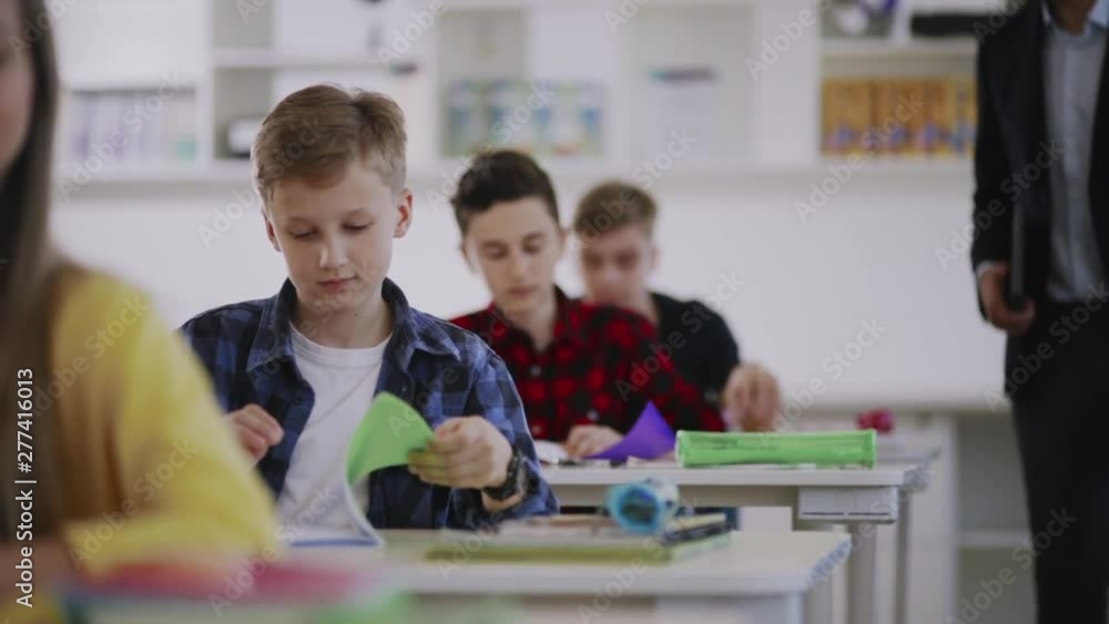 At an english lesson preteen smart sudents opening their notebooks to write down sentences sitting in the classroom. At an english lesson preteen smart sudents opening their notebooks to write down sentences sitting in the classroom.