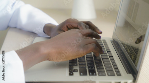 Closeup detail doctor typing on laptop. Female hands entering data on keyboard pc.