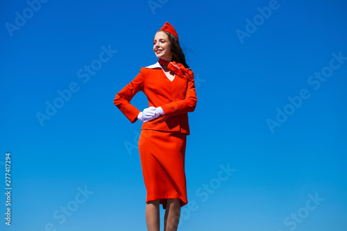 Beautiful stewardess dressed in official red uniform gainst a blue sky photo