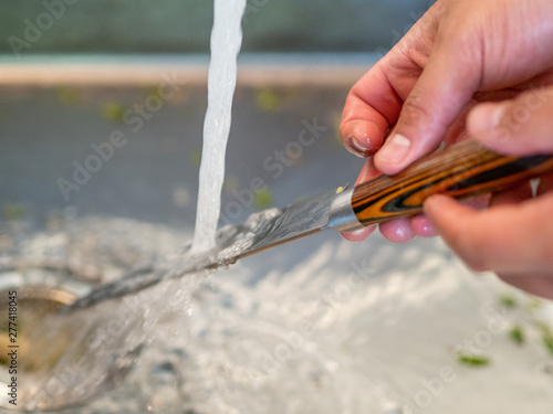 Man's hands washing under the tap a kitchen knife.