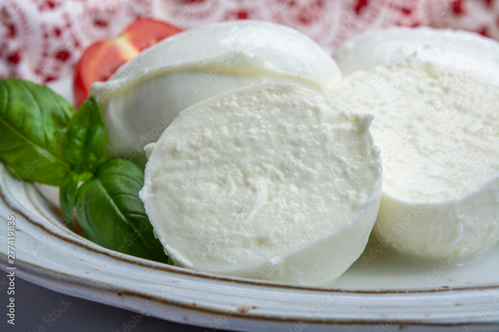 Italian soft cheese mozzarella, white cheese made from cow or buffalo milk with fresh green basil herb and red tomato Italian soft cheese mozzarella, white cheese made from cow or buffalo milk with fresh green basil herb and red tomato